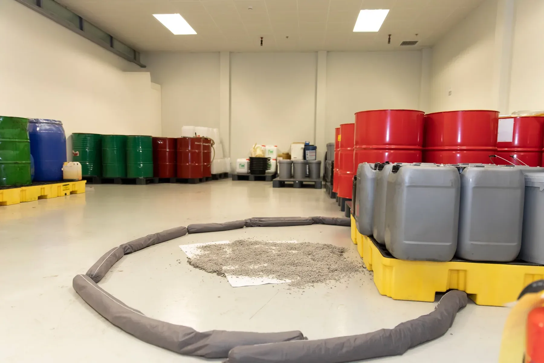 Spill containment barrier around liquid beside stored chemical containers.