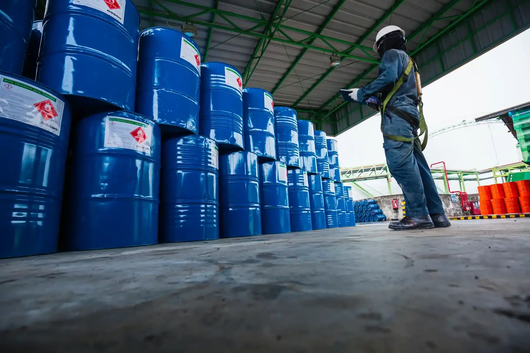 Inspecting blue industrial drums in a chemical storage warehouse.