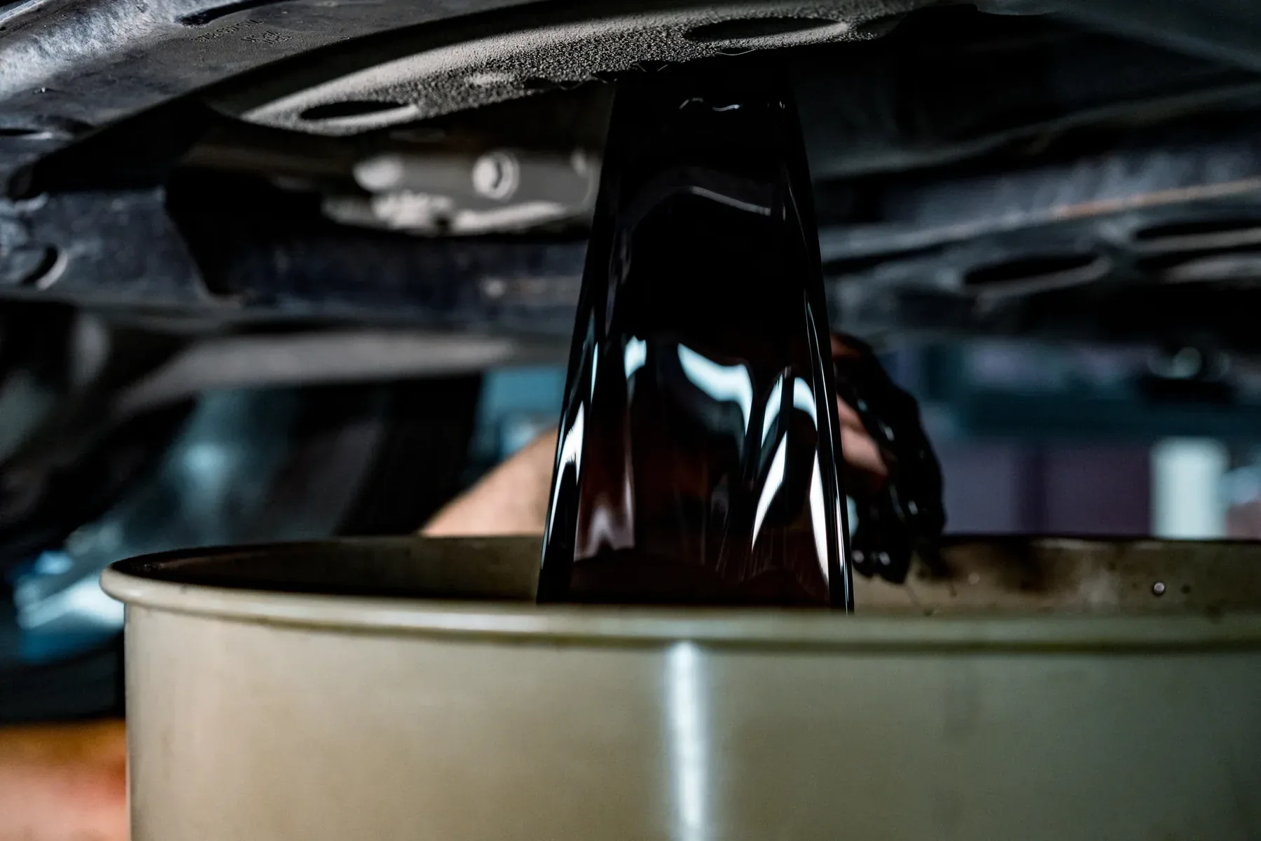 Used engine oil draining into a collection container.