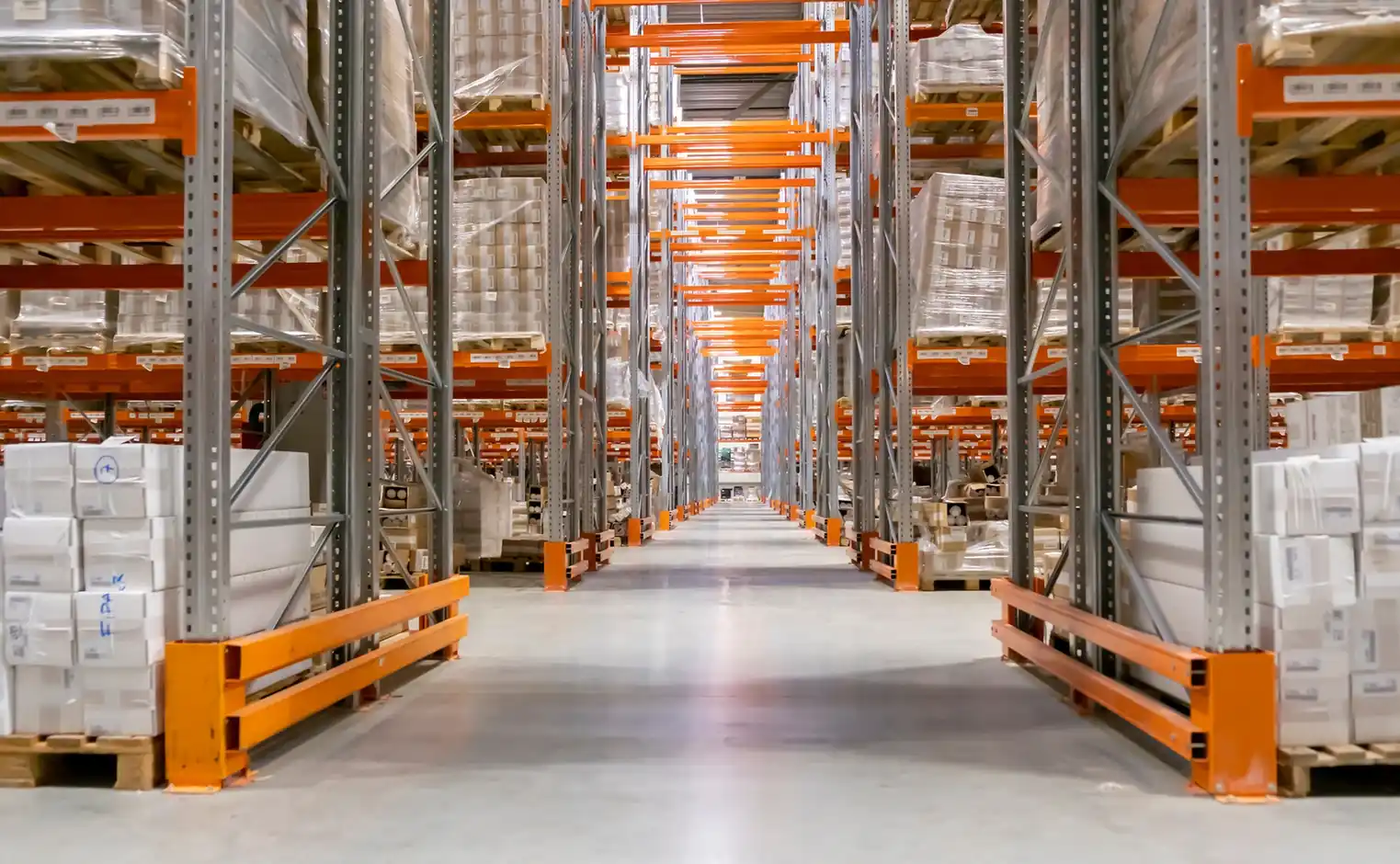 Warehouse aisle lined with racking full of cardboard boxes.