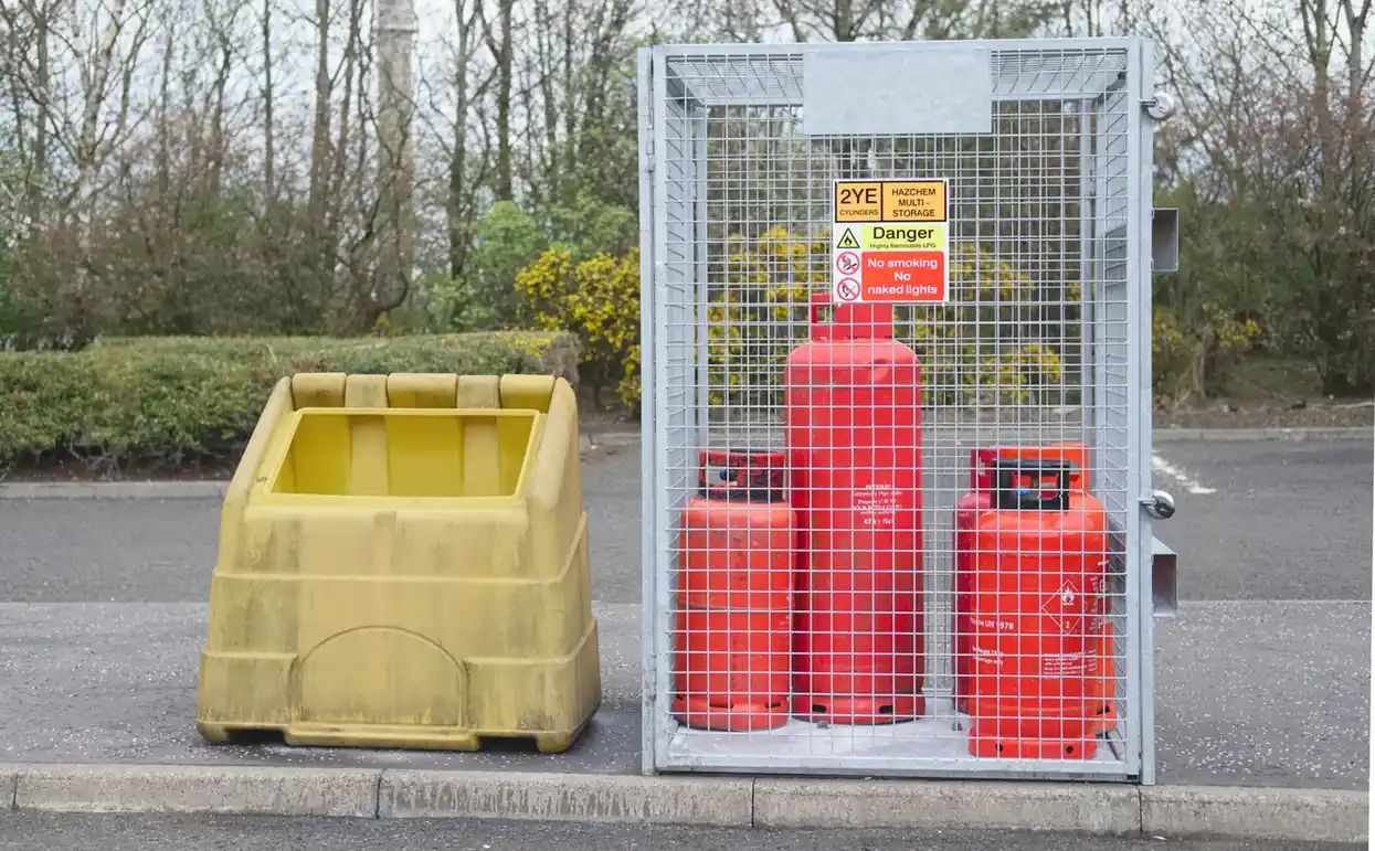 Gas cylinders held in a secure outdoor storage cage.