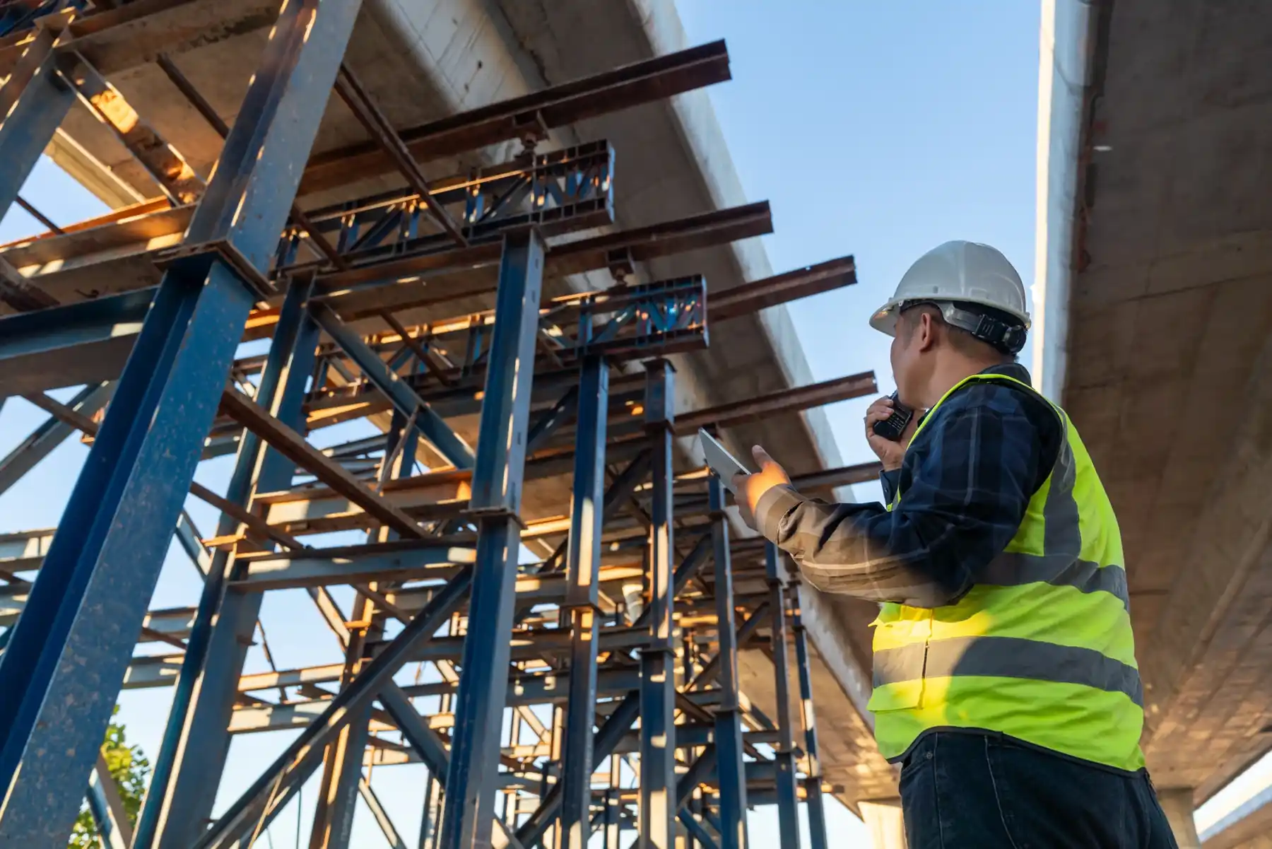 Engineer in a hard hat inspecting a steel structure on a construction project.