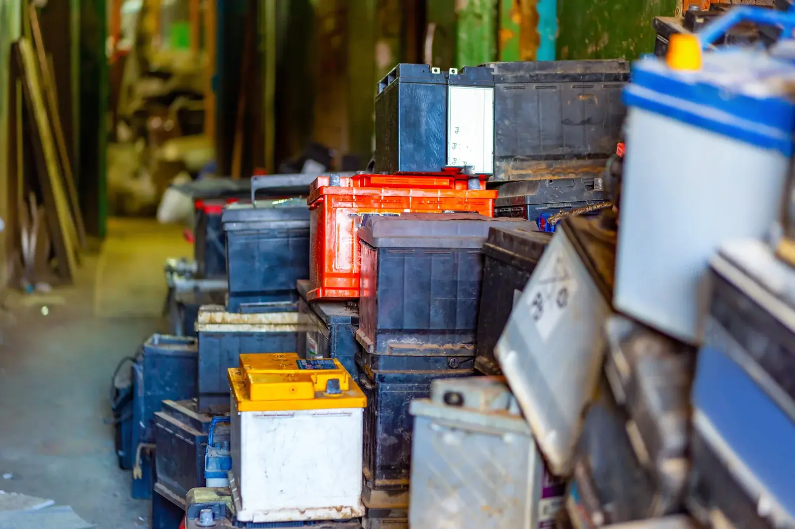 Used vehicle lead-acid batteries stored for recycling at a workshop.