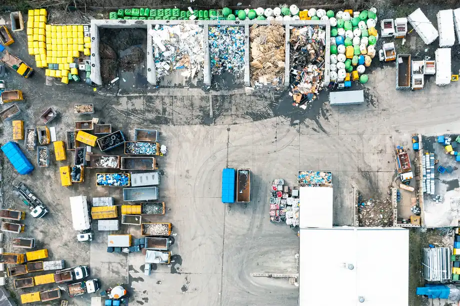 Aerial view of a waste yard with sorted materials, containers and vehicles.