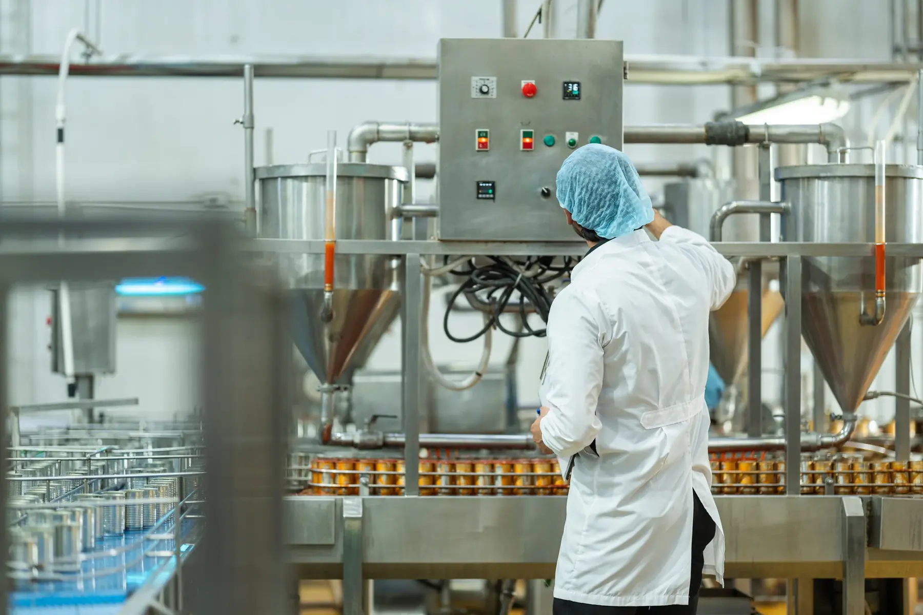 Worker inspecting an automated canning line.