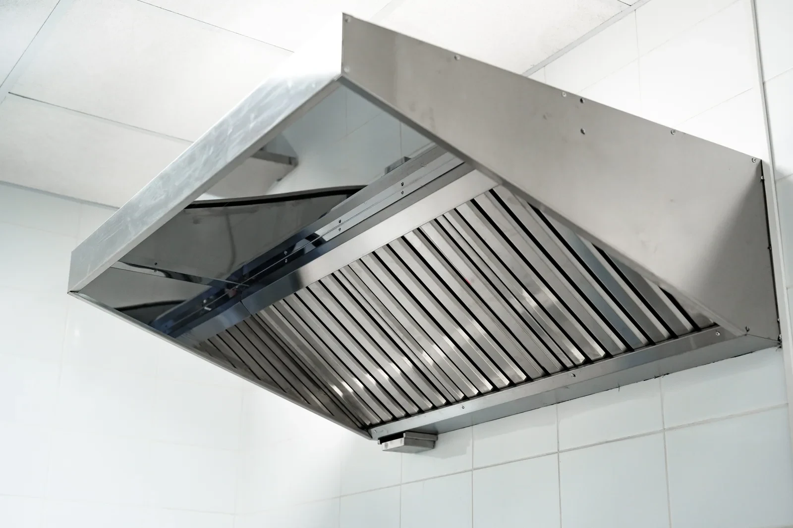 Stainless steel extraction canopy and baffle filters above a commercial kitchen.