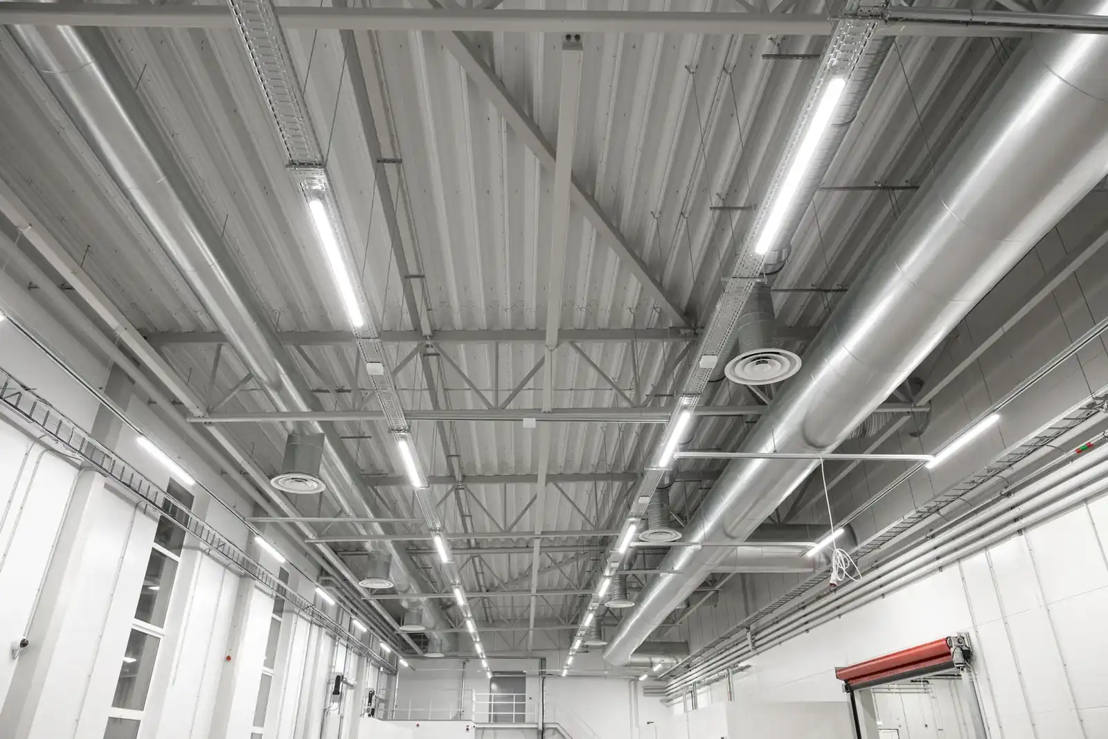 Roof beams, lights and ventilation ducts above a high industrial workspace.