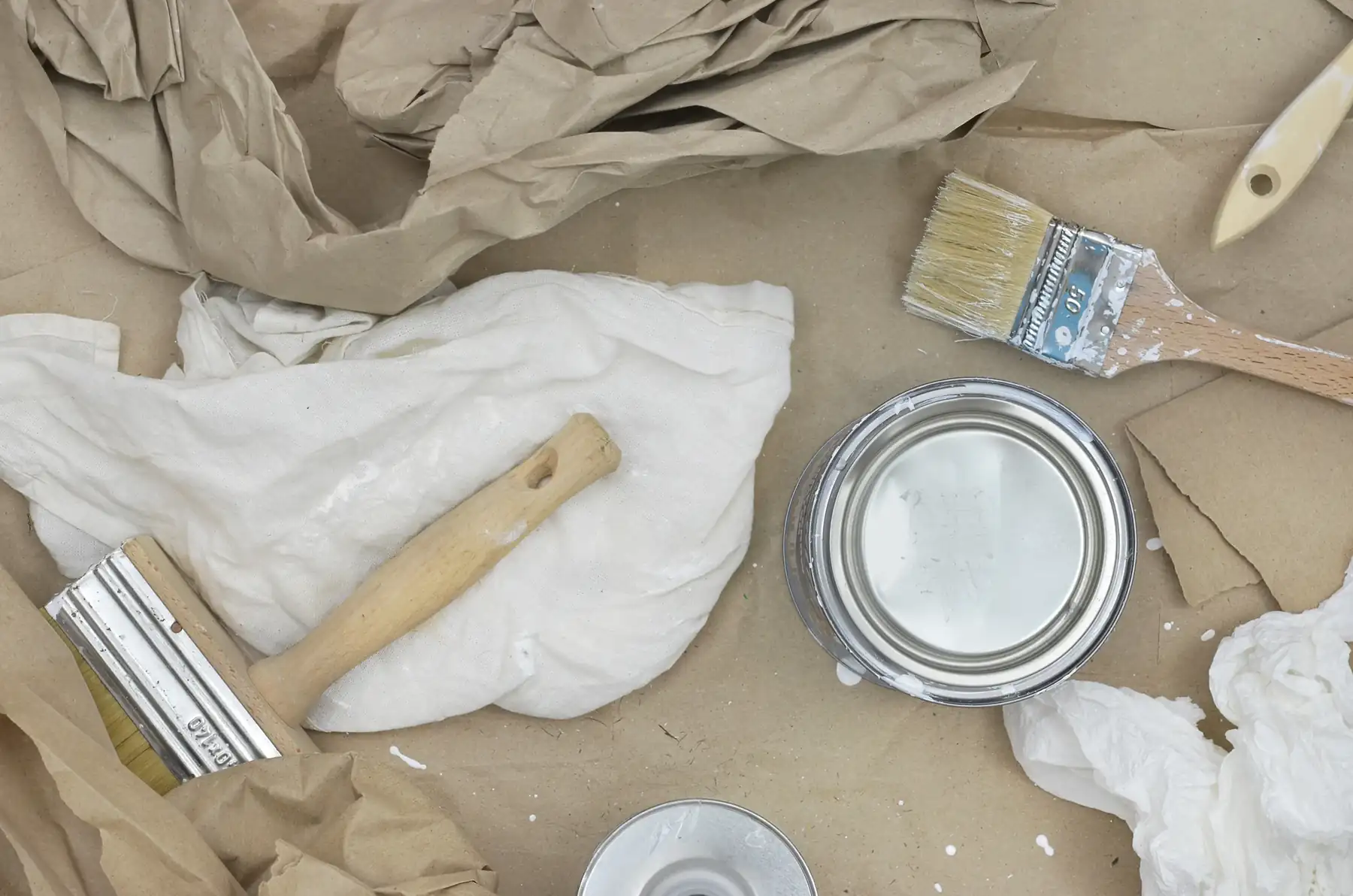 Used paintbrushes, a paint tin and cloths left after decorating.