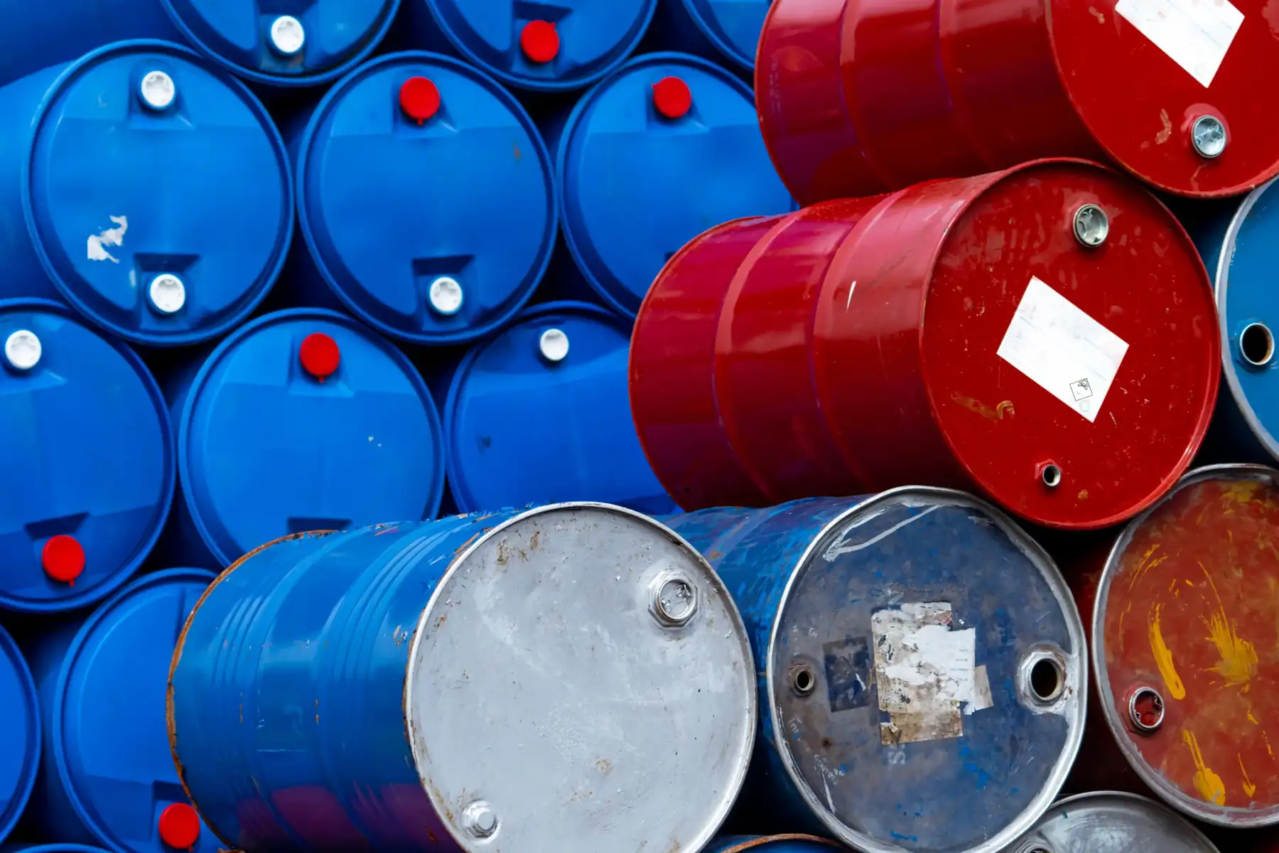 Stacked used blue and red chemical drums.