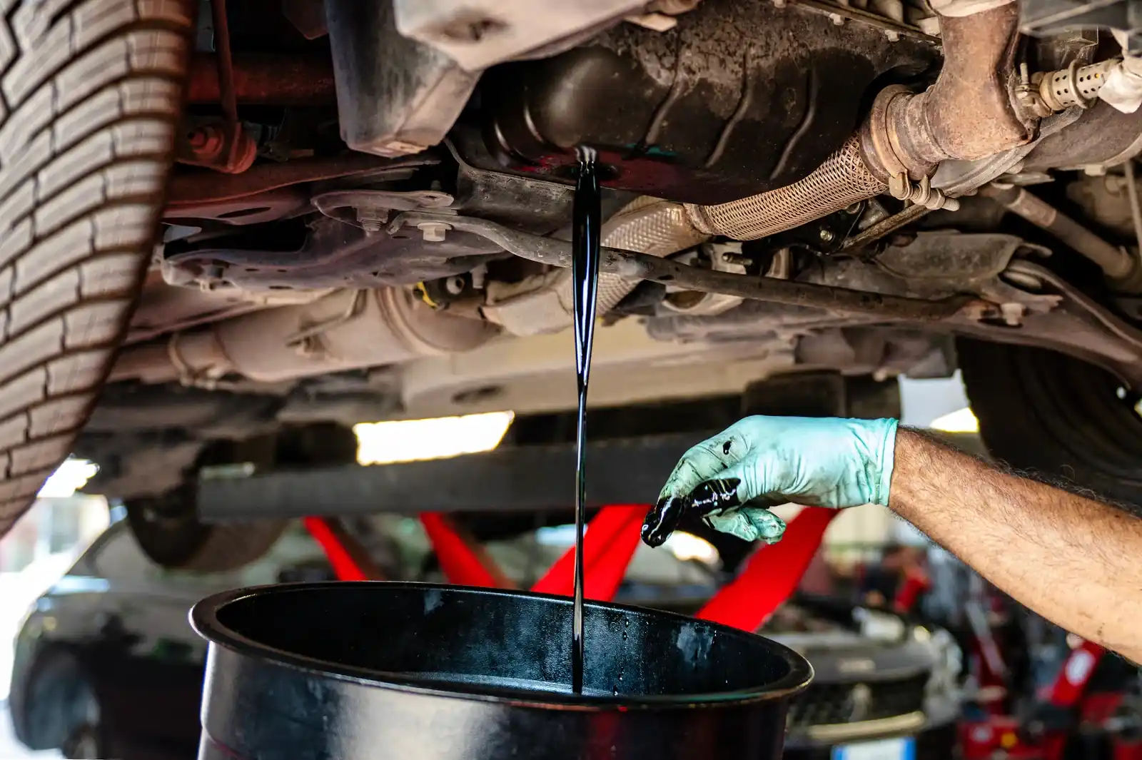 Used engine oil draining into a collection vessel in a workshop.