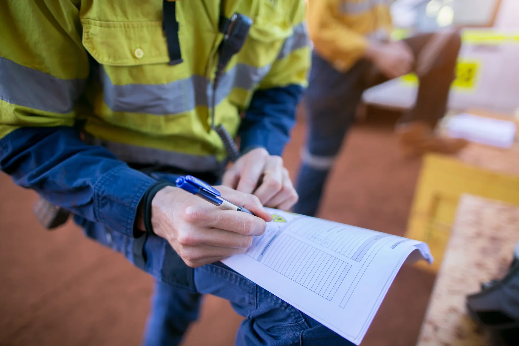 Worker filling in a permit form on a clipboard.